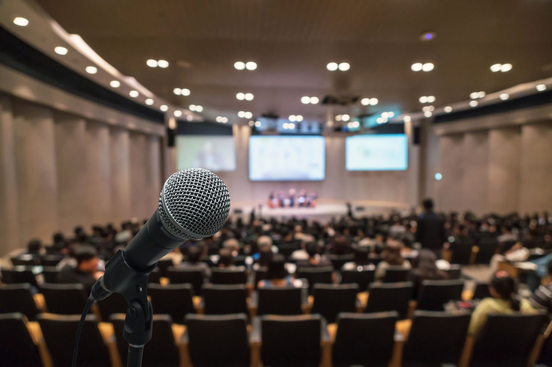 A microphone is sitting in front of a crowd of people in an auditorium.