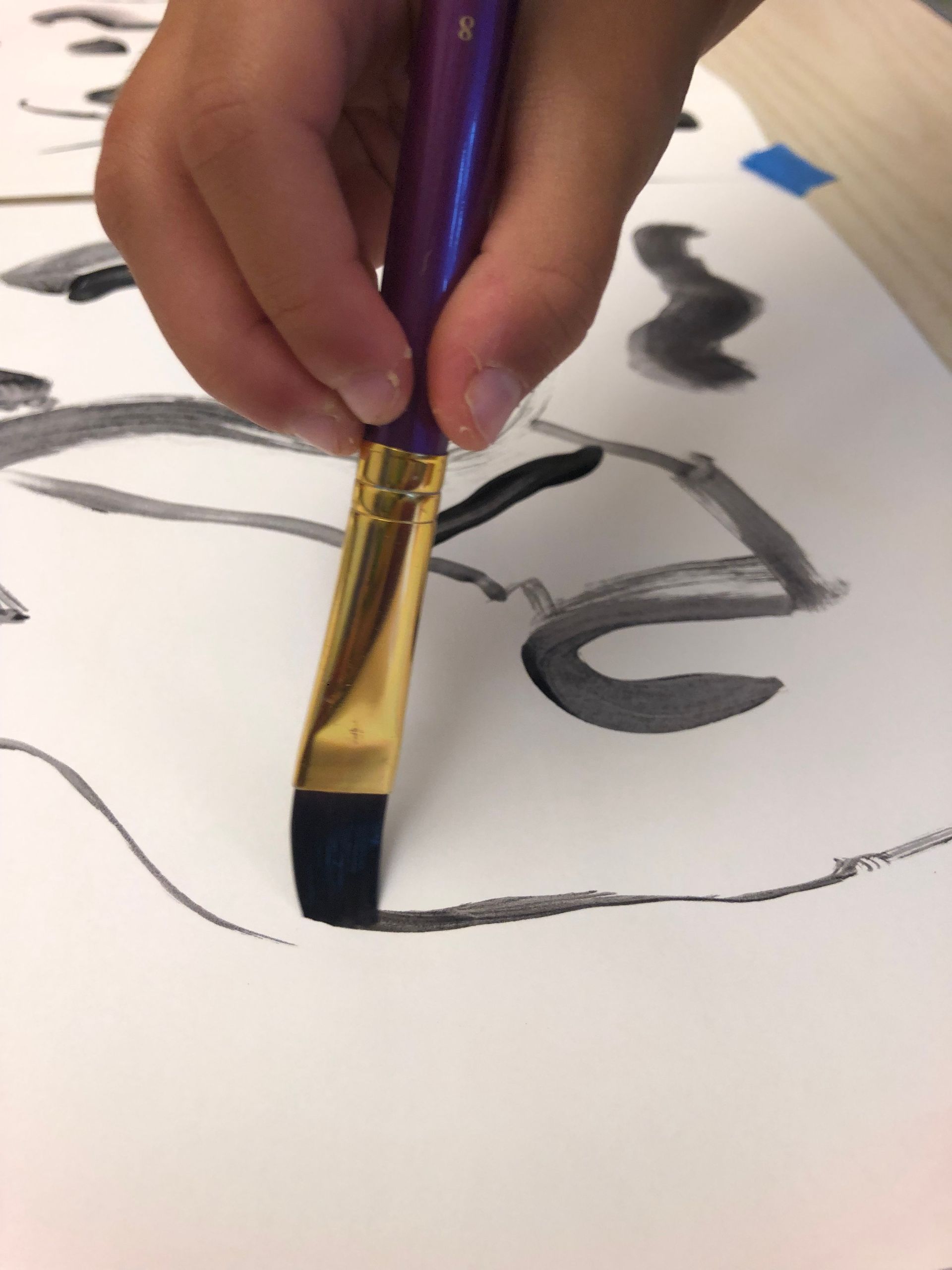 A person is using a purple brush to paint on a piece of paper