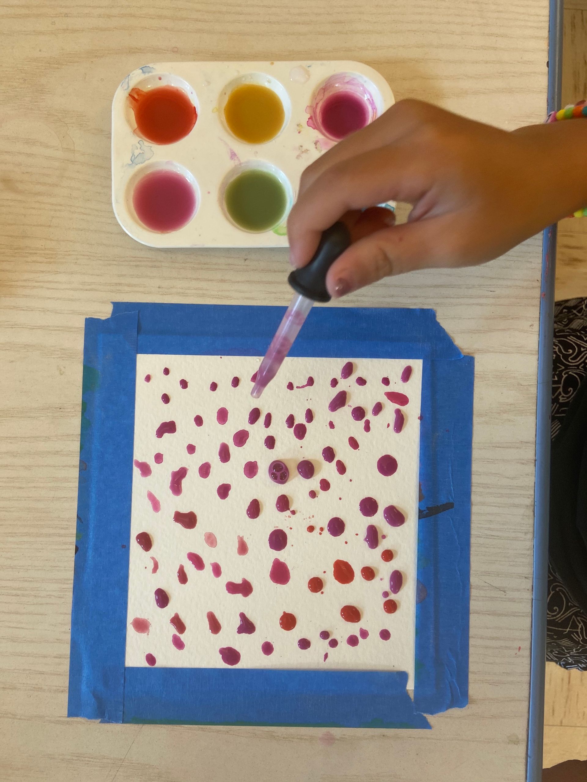A child is painting a picture with a dropper