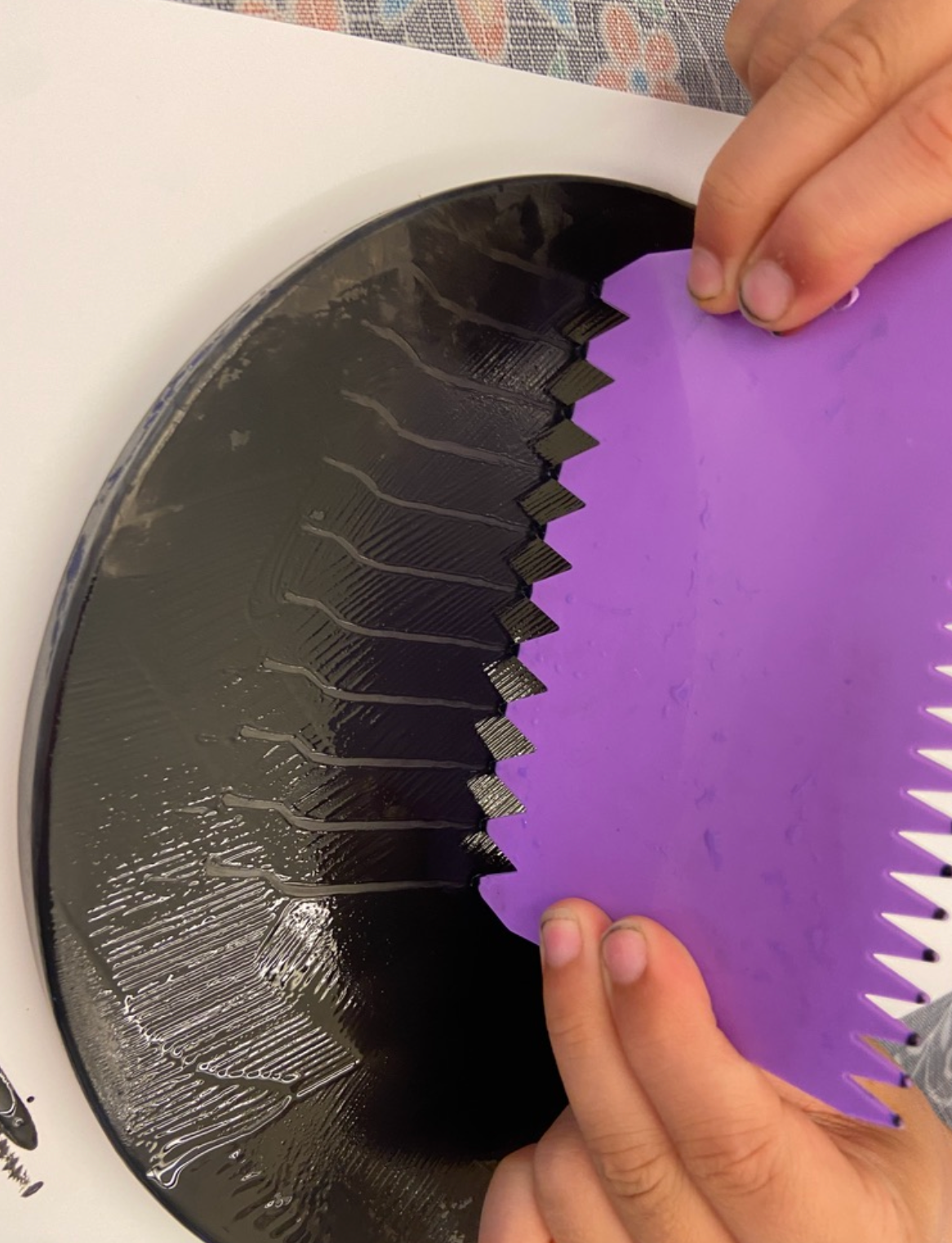 A person is holding a purple spatula over a black plate