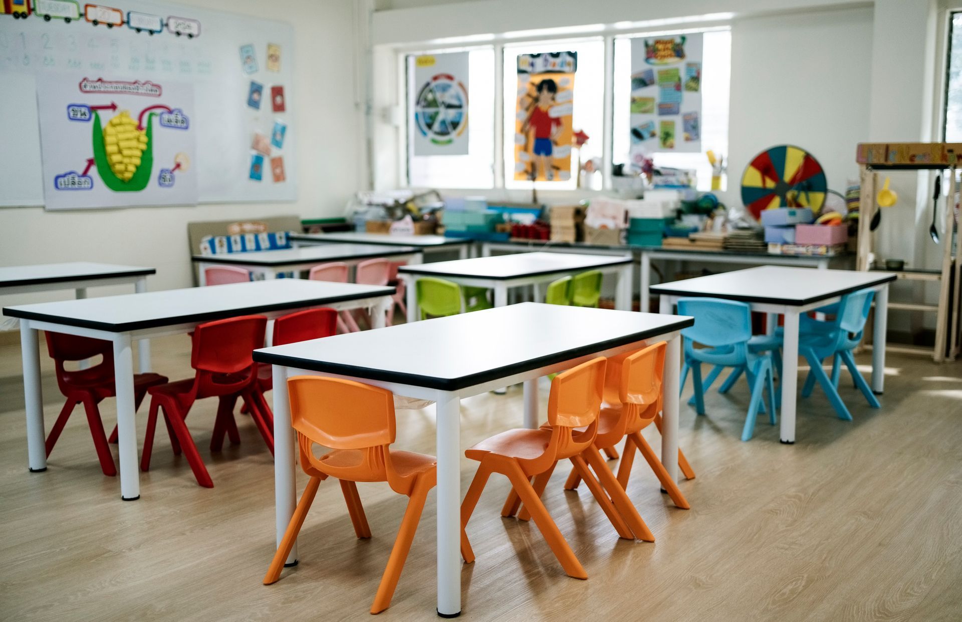 There are many tables and chairs in the classroom.