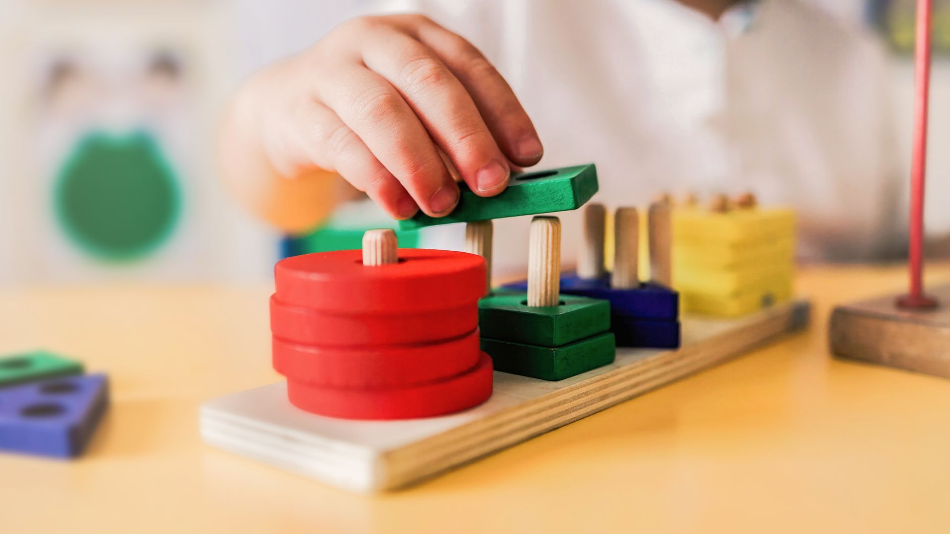 A child is playing with a wooden toy on a table.
