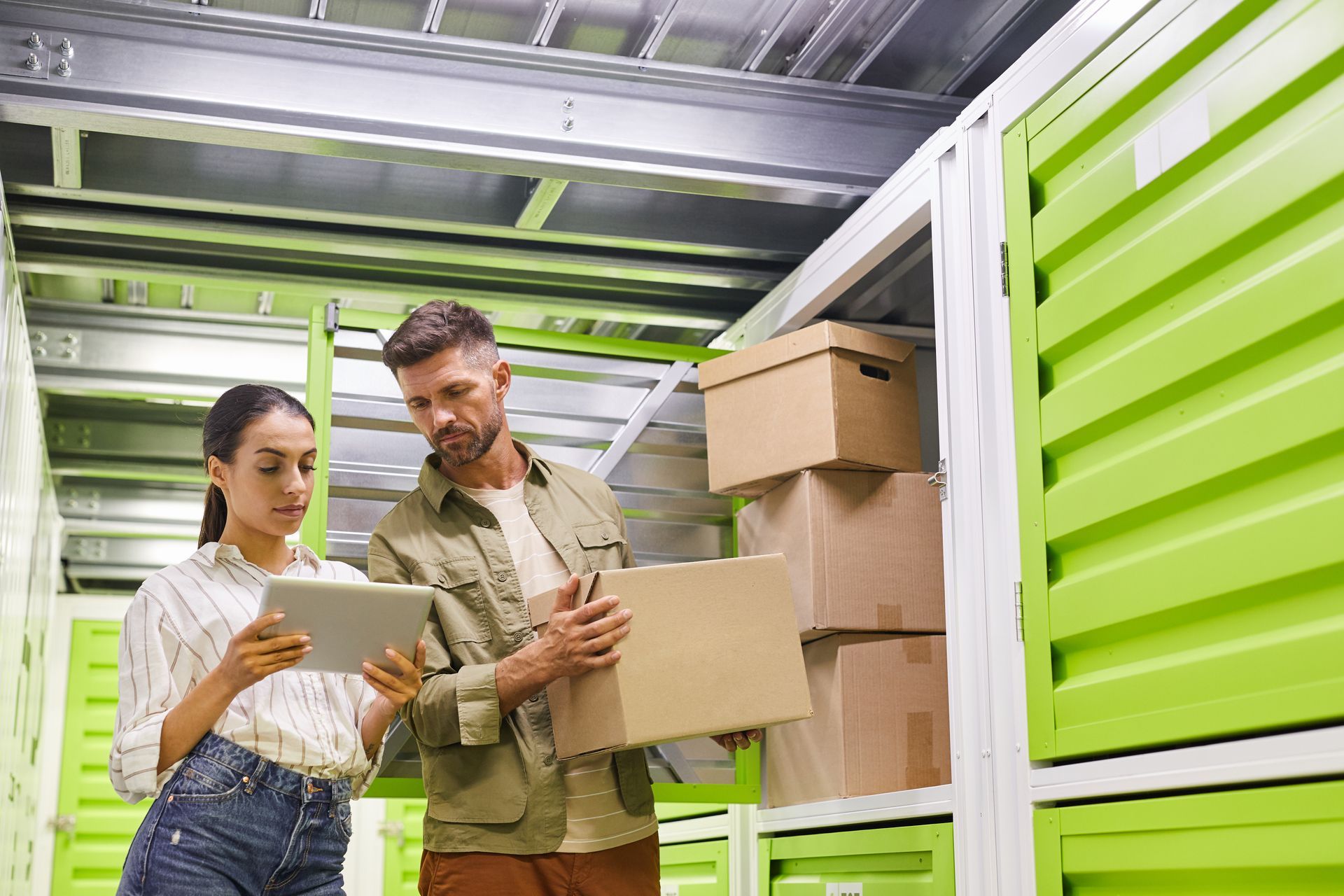 A man and a woman are looking at a tablet in a storage unit.