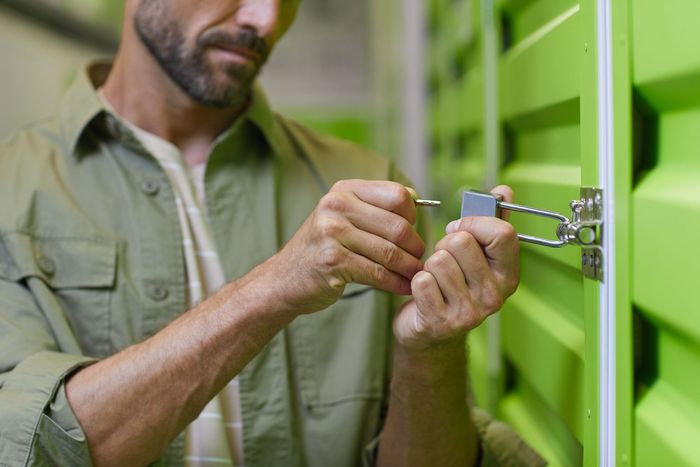 A man is locking a green door with a padlock.