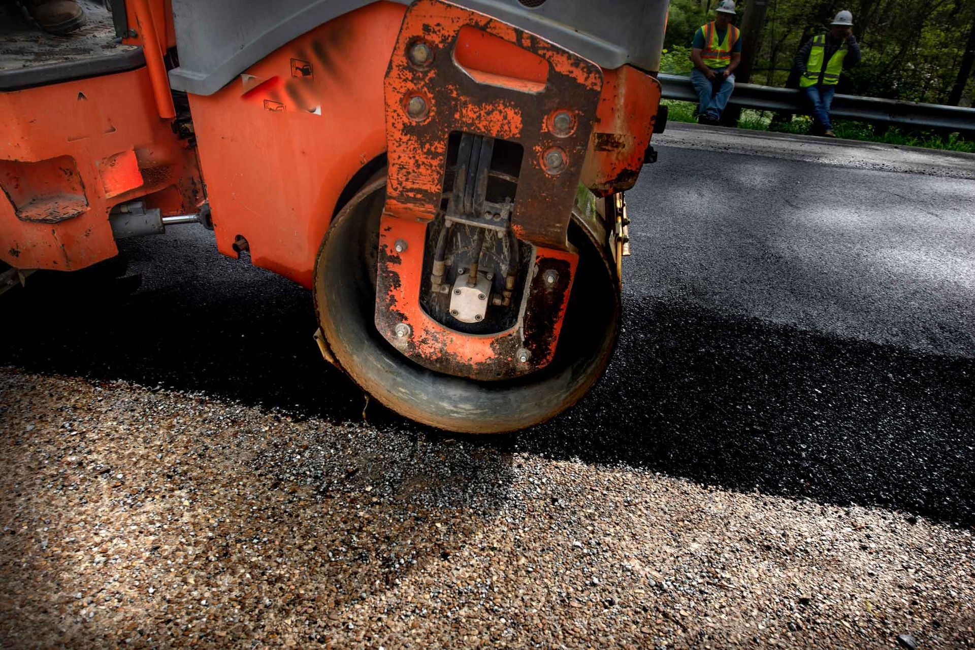 A machine steamrolls fresh, hot asphalt for a smooth, lasting finish. A machine steamrolls fresh, hot asphalt for a smooth, lasting finish.