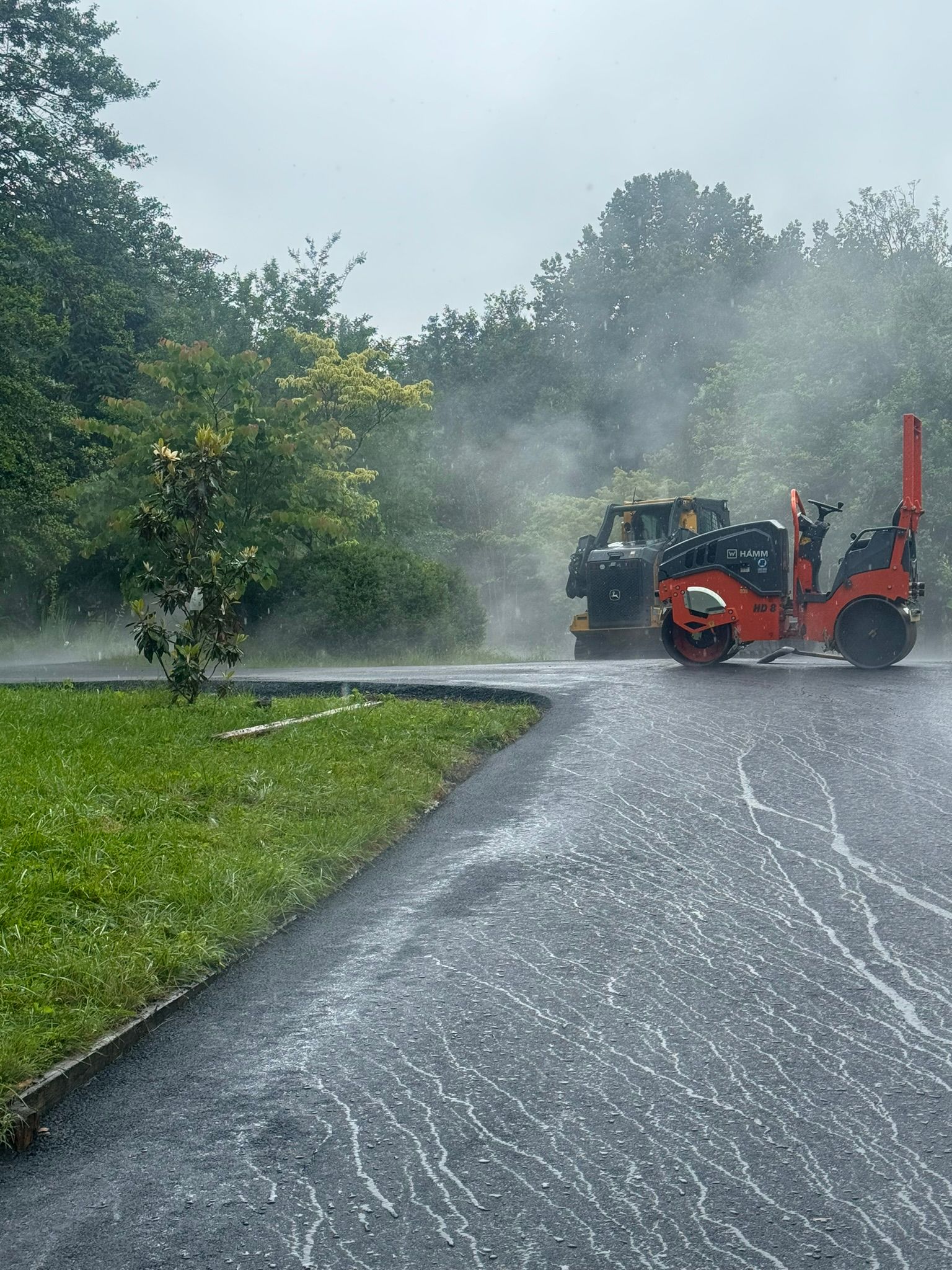 A couple of trucks are driving down a road in the rain.