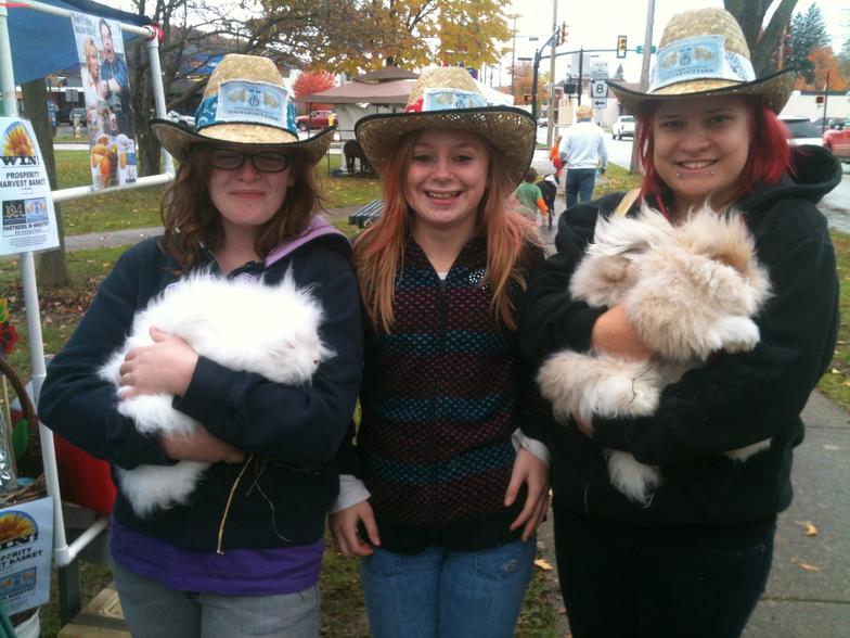 Three girls wearing cowboy hats are holding rabbits