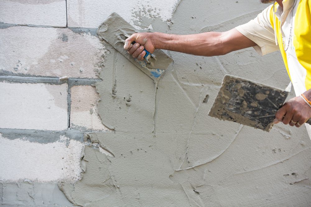 Person Applying Cement to a Cinder Block Wall — RAC Carpentry Services in Oxenford, QLD