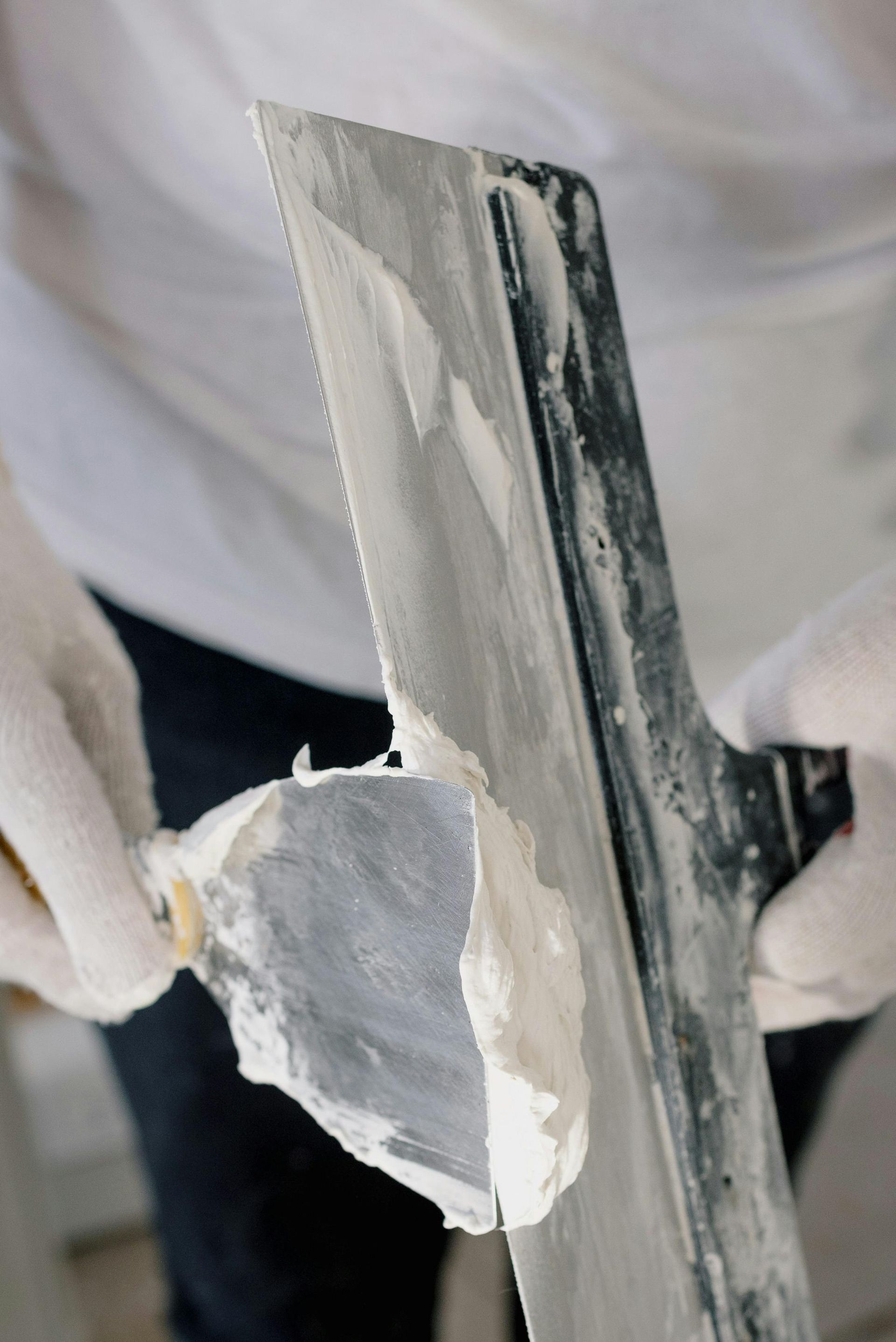 Hands Wearing White Gloves Use a Putty Knife — RAC Carpentry Services in Labrador, QLD