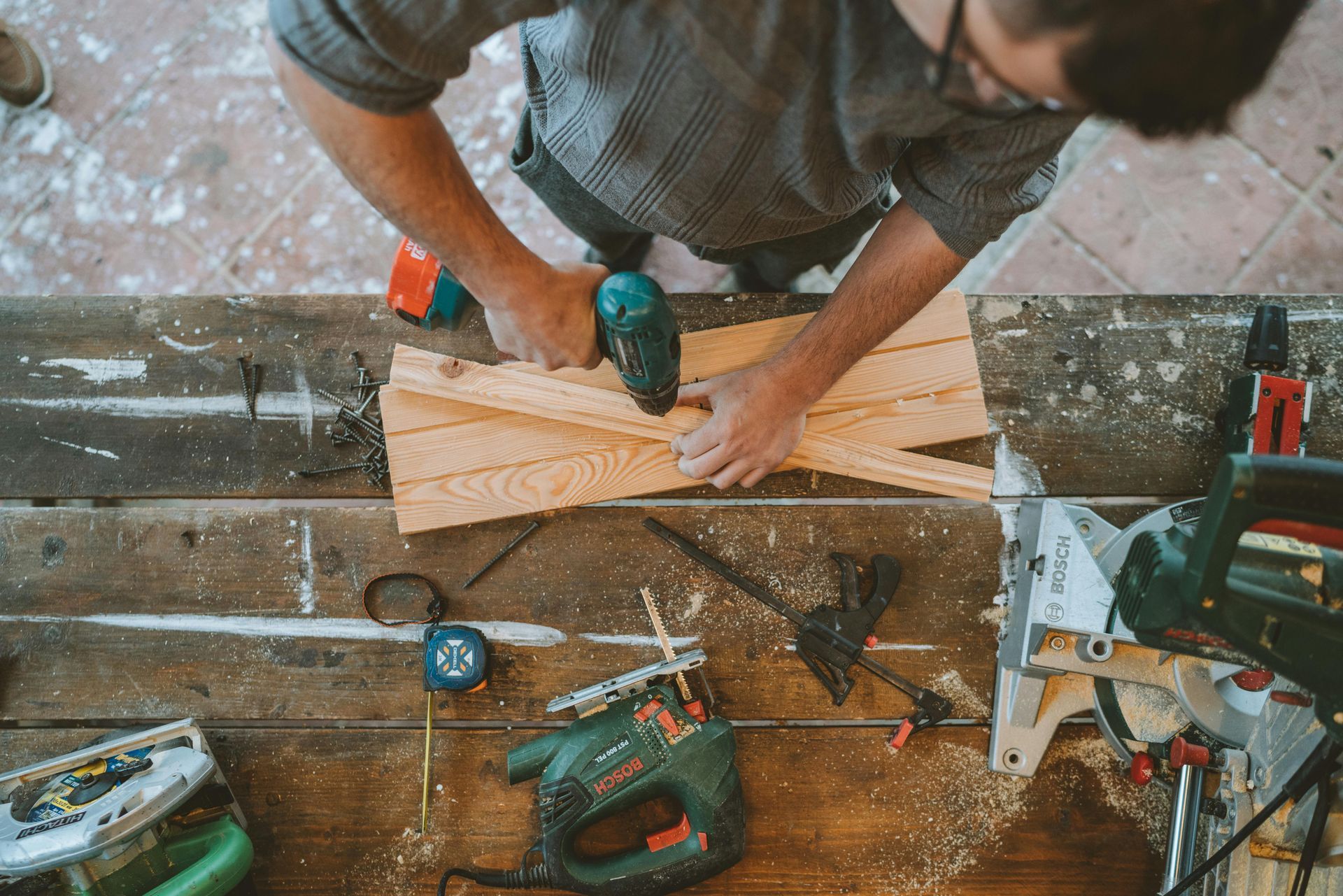 A Person Uses a Handheld Drill on a Wooden Project — RAC Carpentry Services in Labrador, QLD