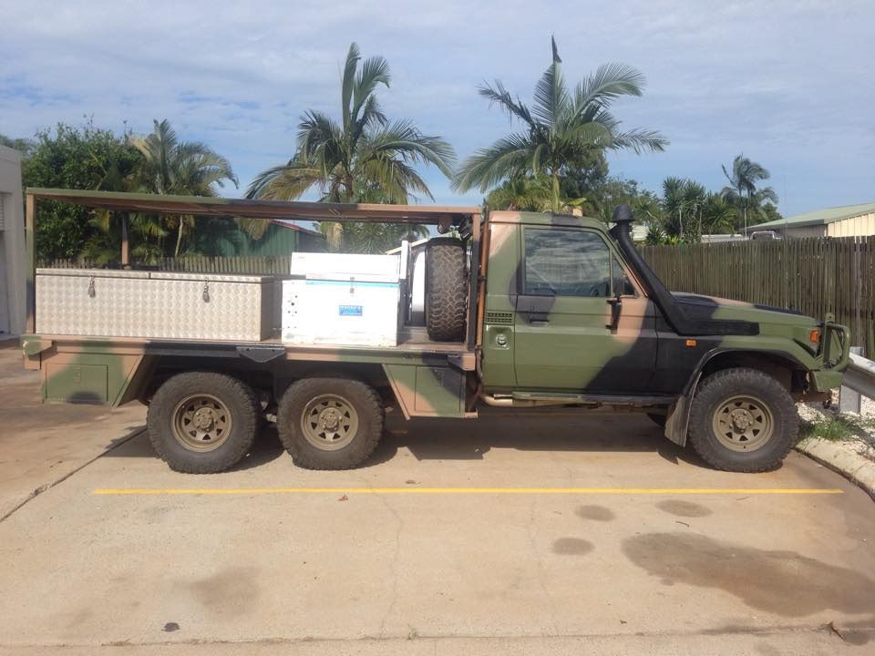 A Military Truck is Parked in a Parking Lot With Palm Trees in the Background — Mr Shiny Mechanical in Moranbah, QLD