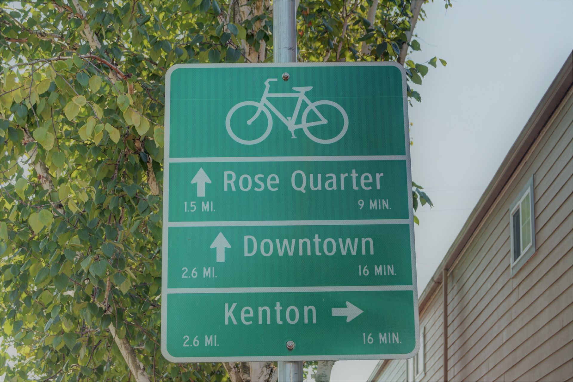 Green bicycle route sign indicating directions to Rose Quarter, Downtow , and Kenton