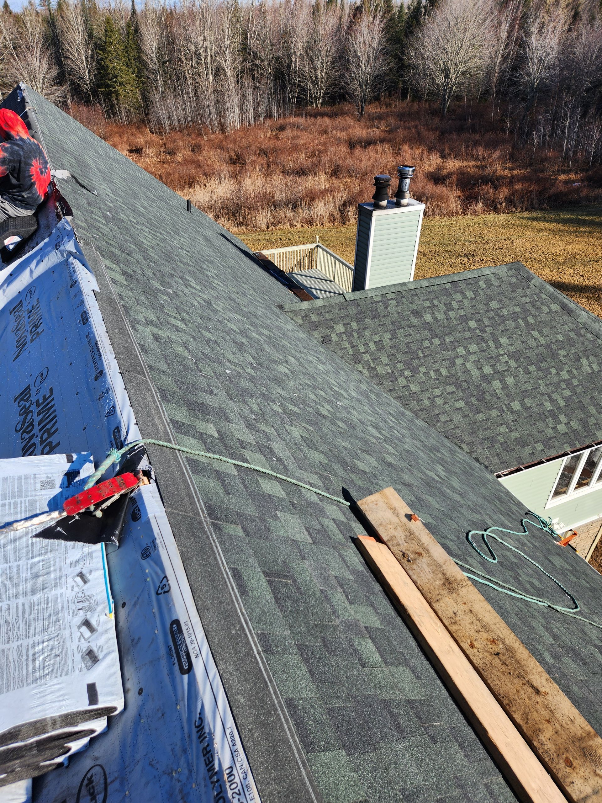 A roof is being installed on a house with a chimney.