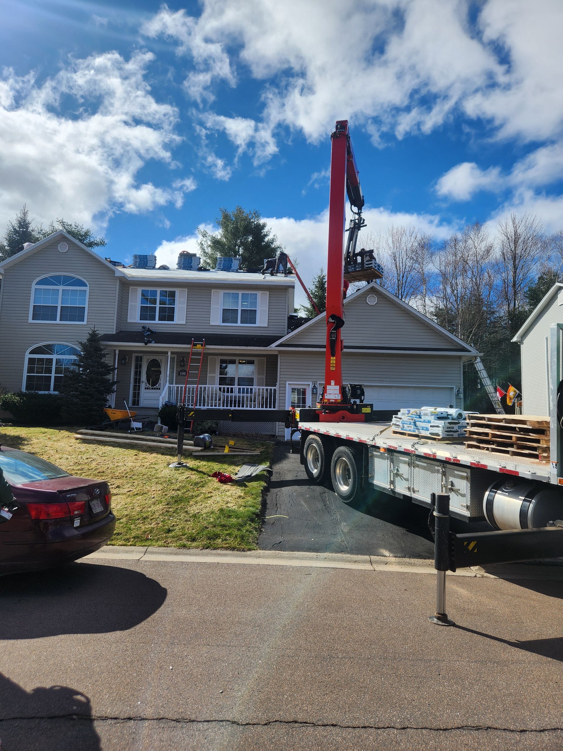 A truck is parked in front of a house with a crane on the back of it.