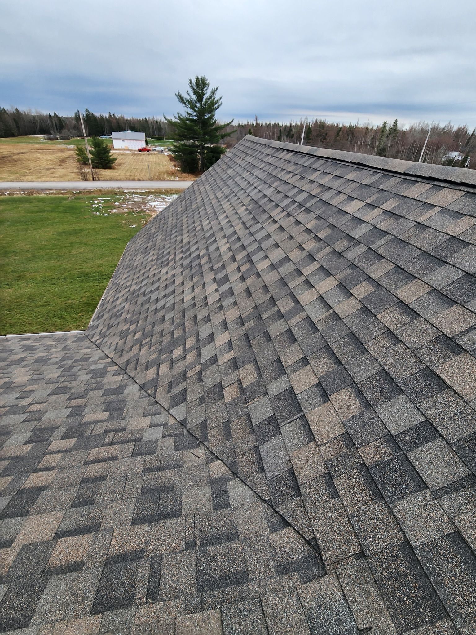 A roof with a lot of shingles on it and a field in the background.