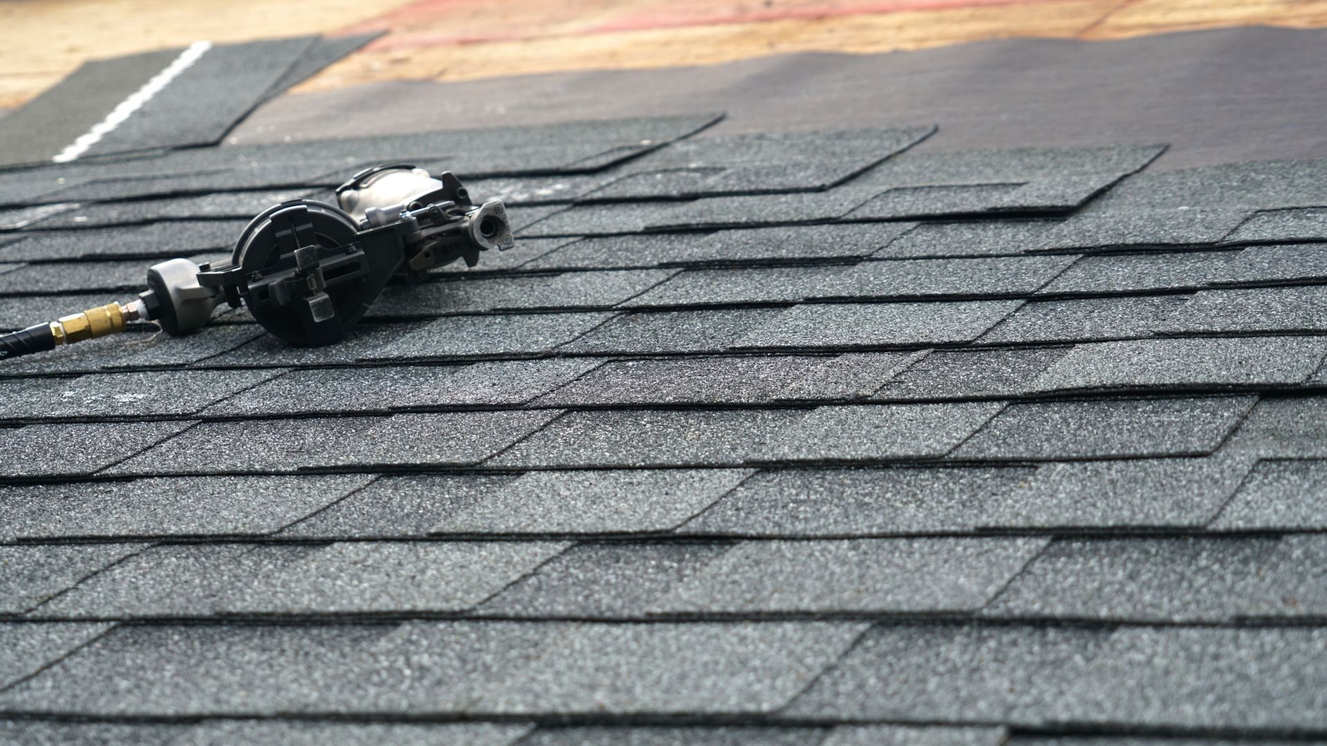 A close up of a roof with shingles and a tool on it.