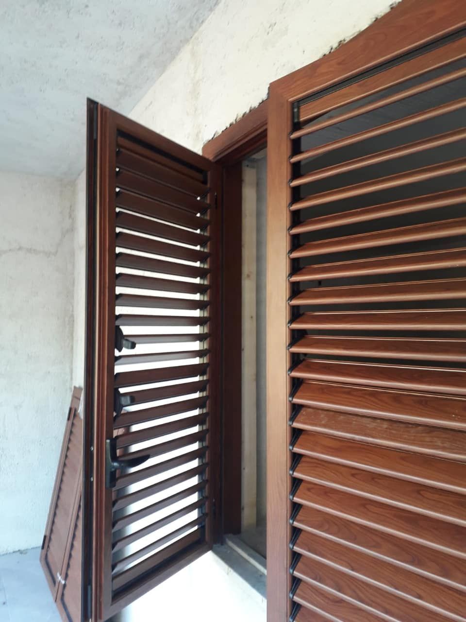 Una porta con persiane di legno è aperta su un balcone