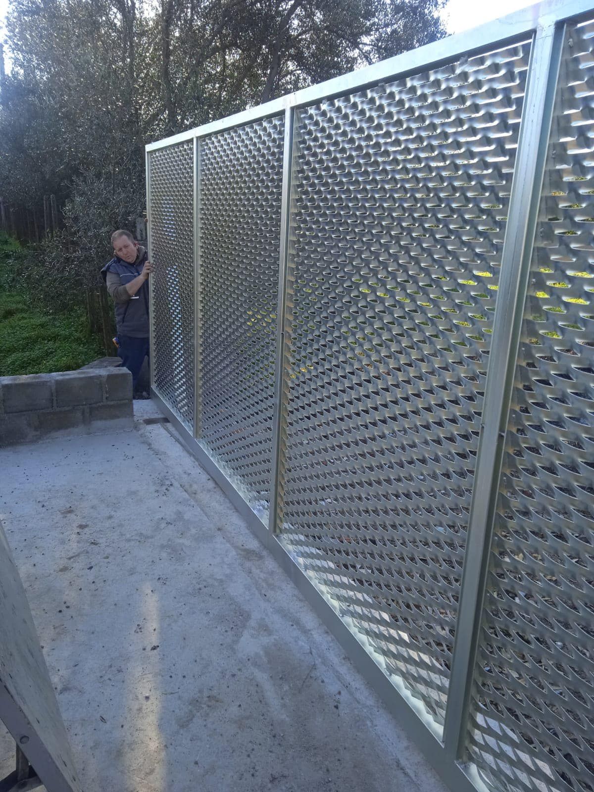 Un uomo è in piedi dietro una recinzione di acciaio inossidabile.