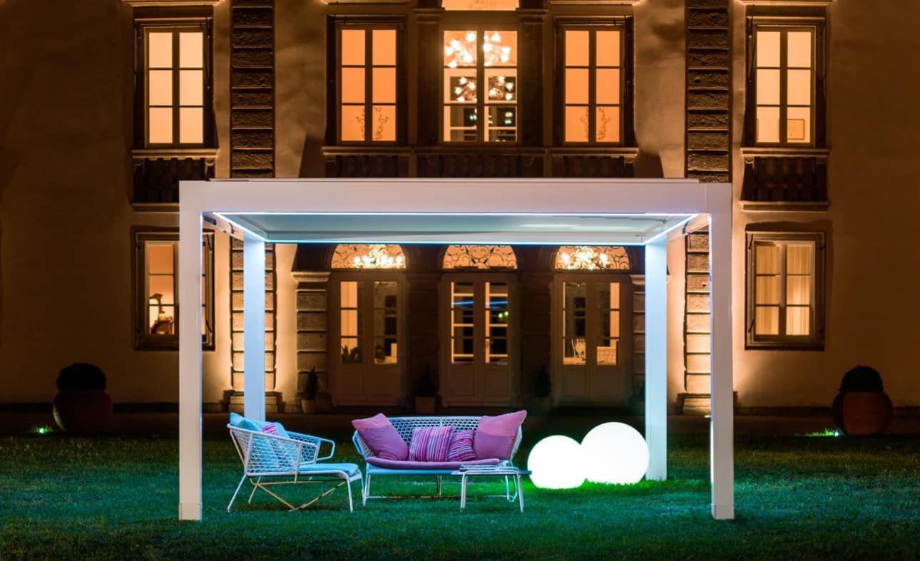 Un pergolato con un divano e delle sedie sotto di esso di fronte a un edificio