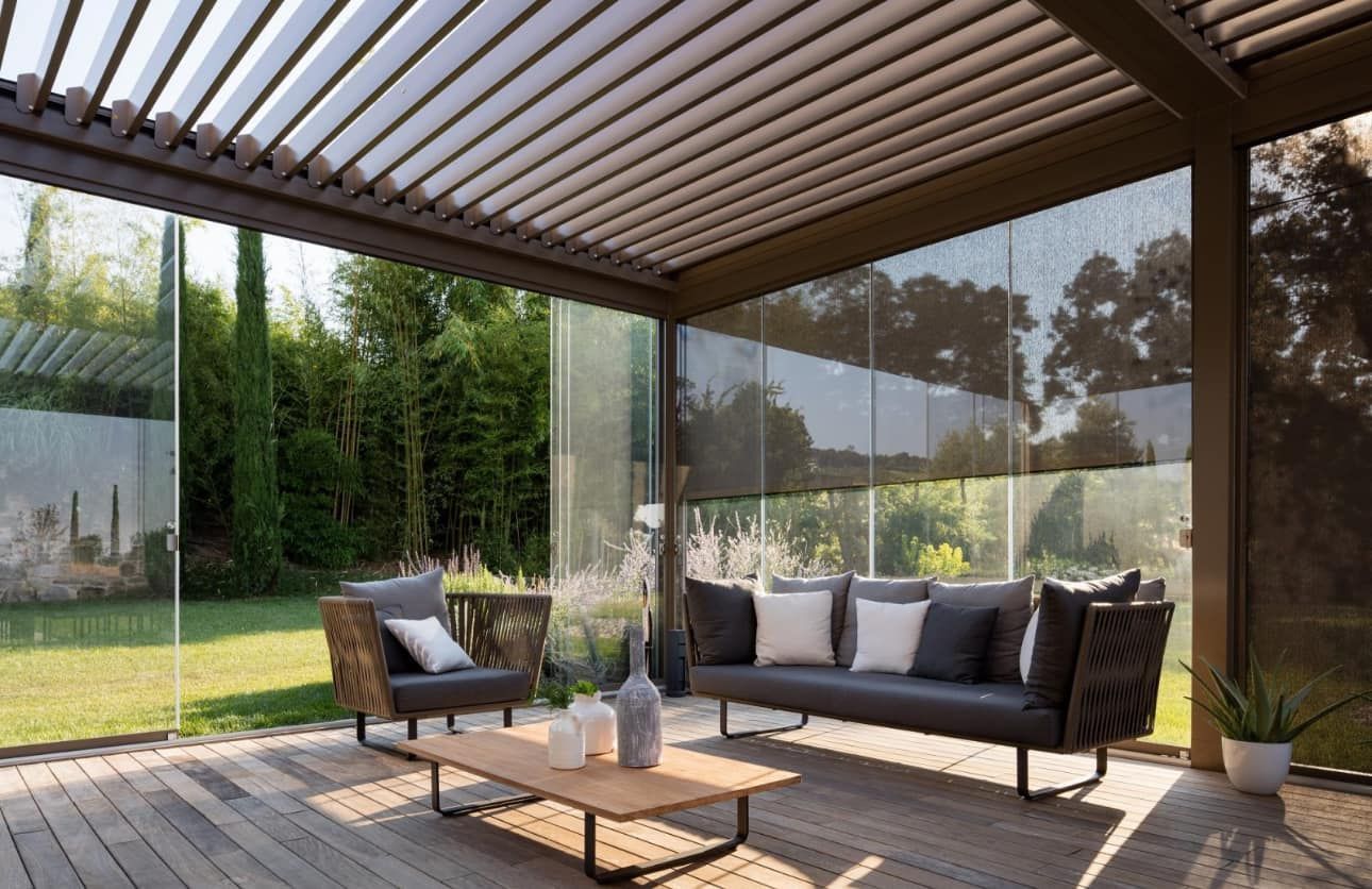 Un patio con un divano, sedie e un tavolino da caffè sotto un pergolato.