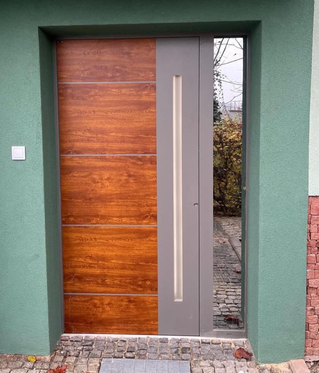 Una porta di legno con una cornice grigia è su una parete verde