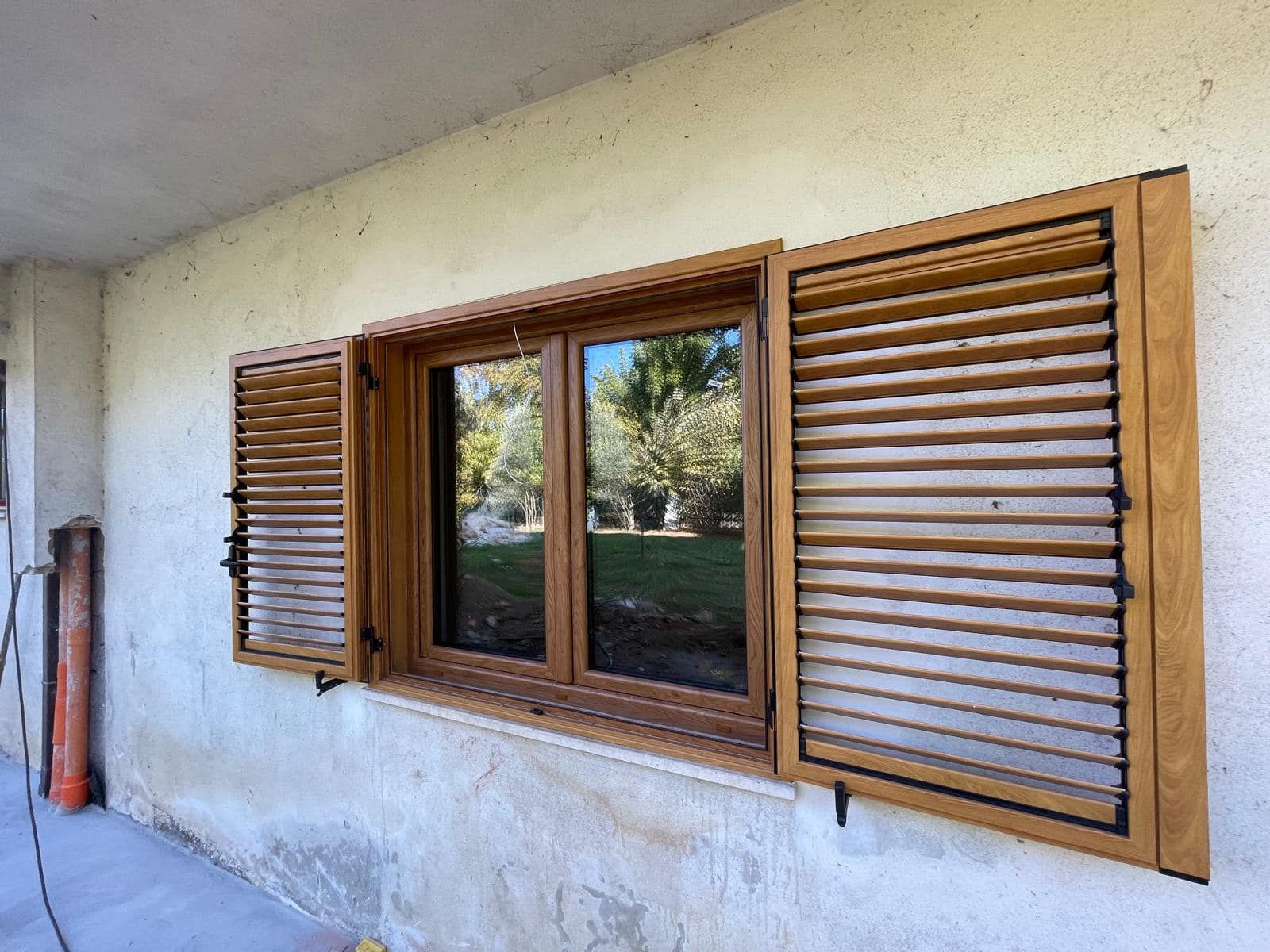 Una finestra con persiane di legno su una parete bianca.