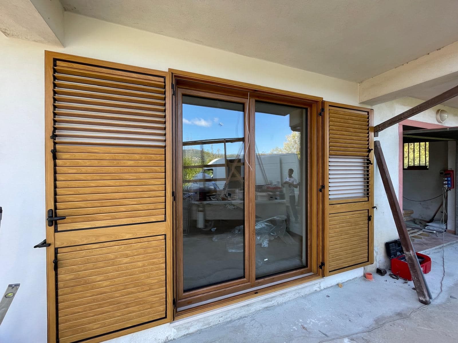 Una porta scorrevole in vetro con persiane in legno su una parete bianca.