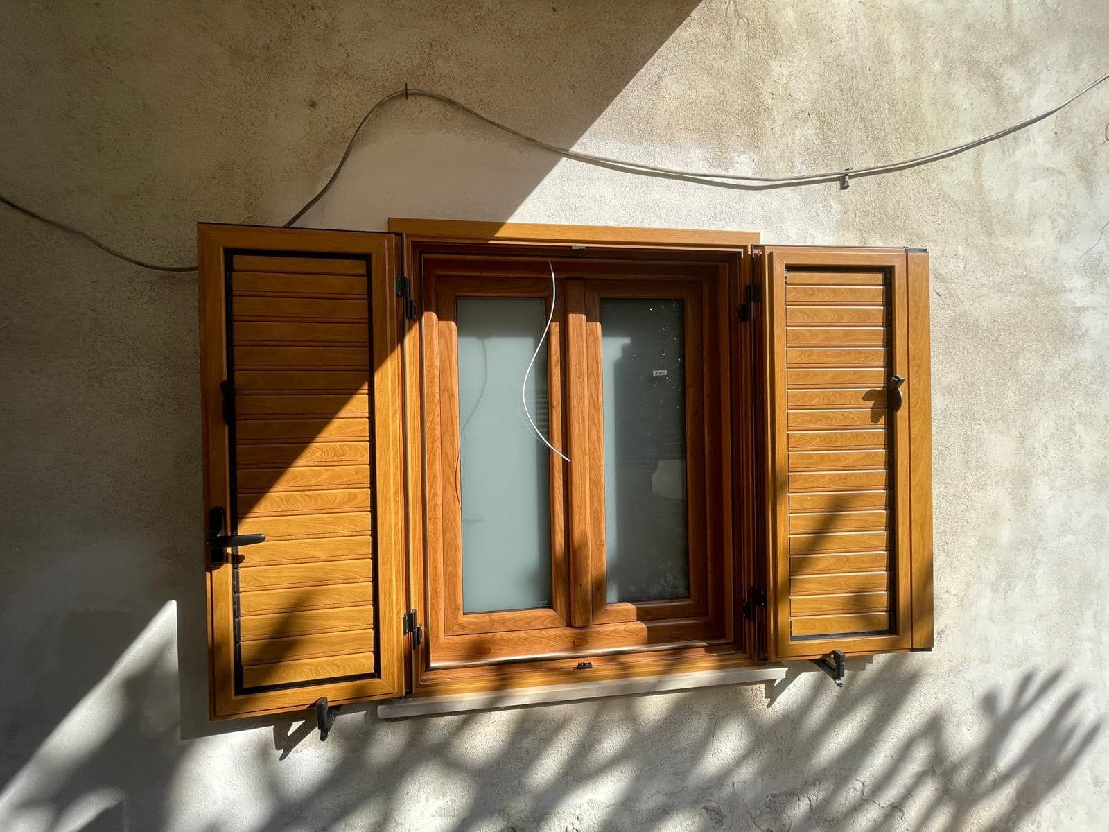 Una finestra con persiane di legno su un muro bianco