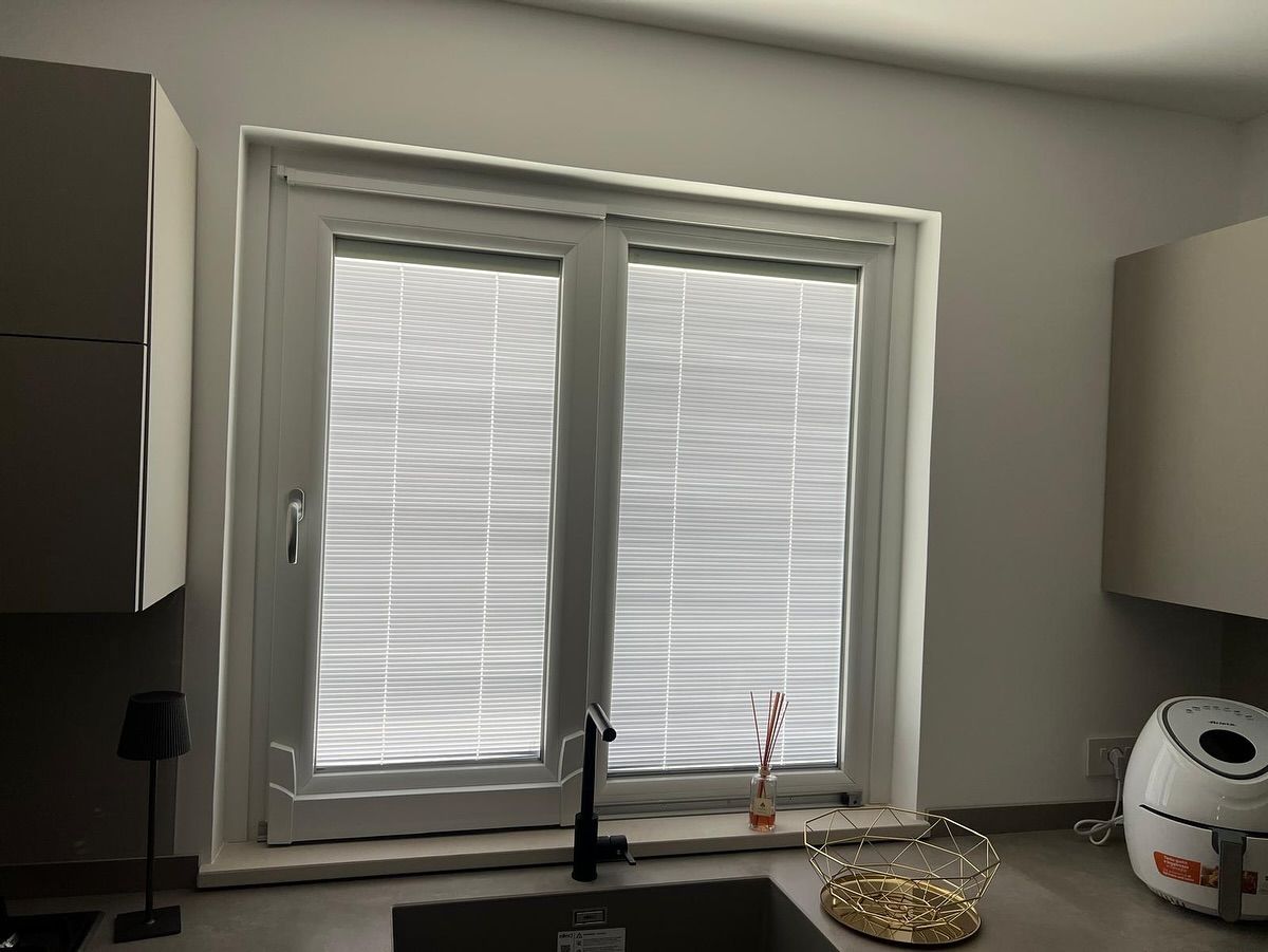 Una cucina con un lavandino e una finestra con le persiane.