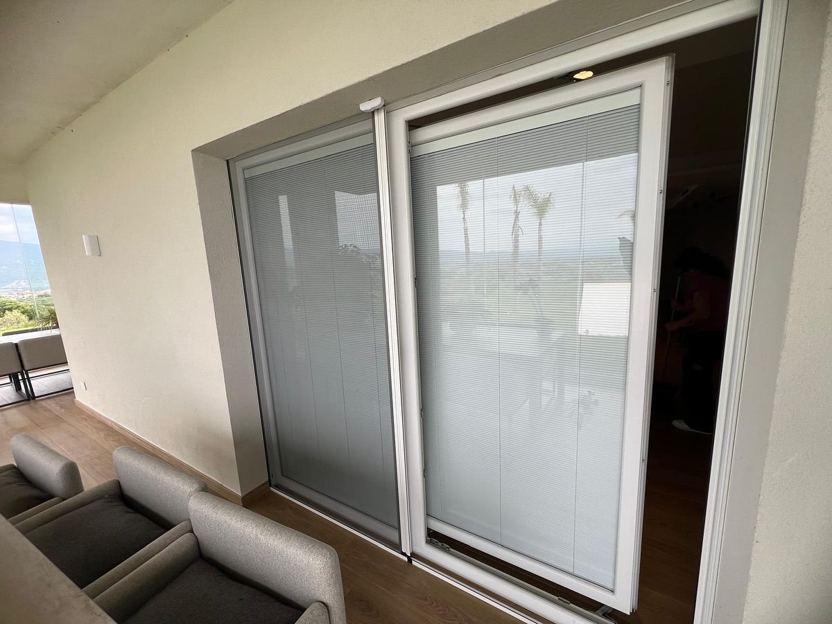 Una porta scorrevole in vetro si apre su un balcone con sedie.