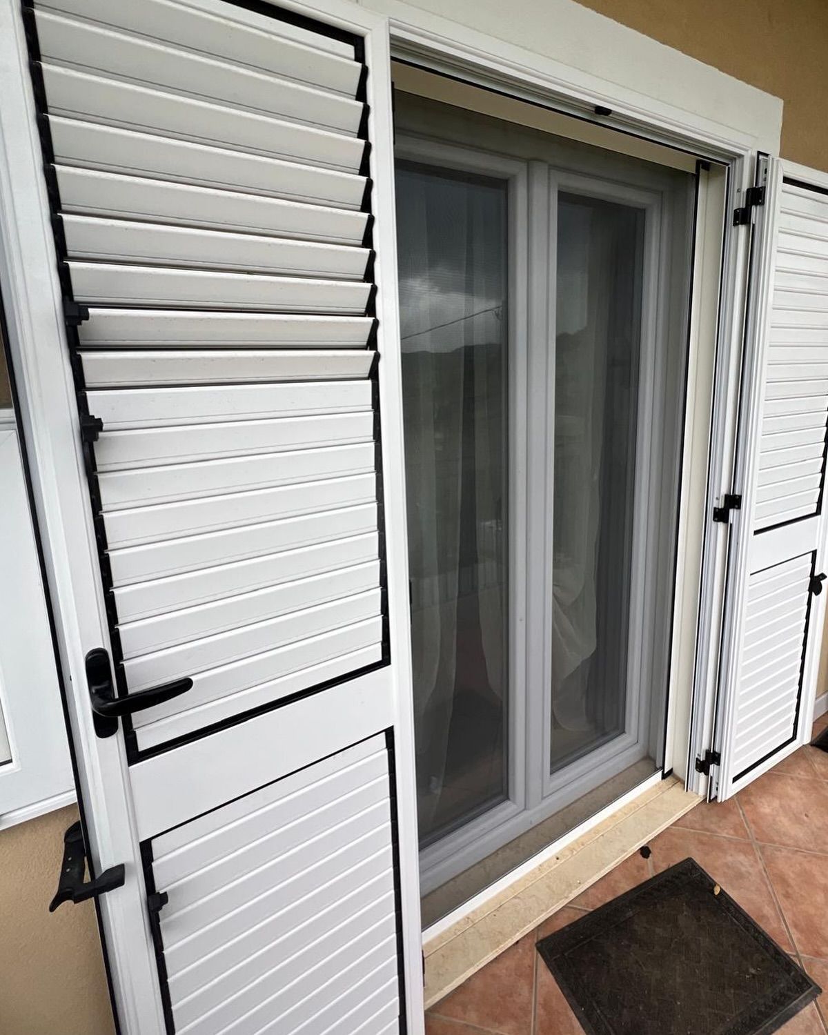 Una porta scorrevole in vetro con persiane bianche