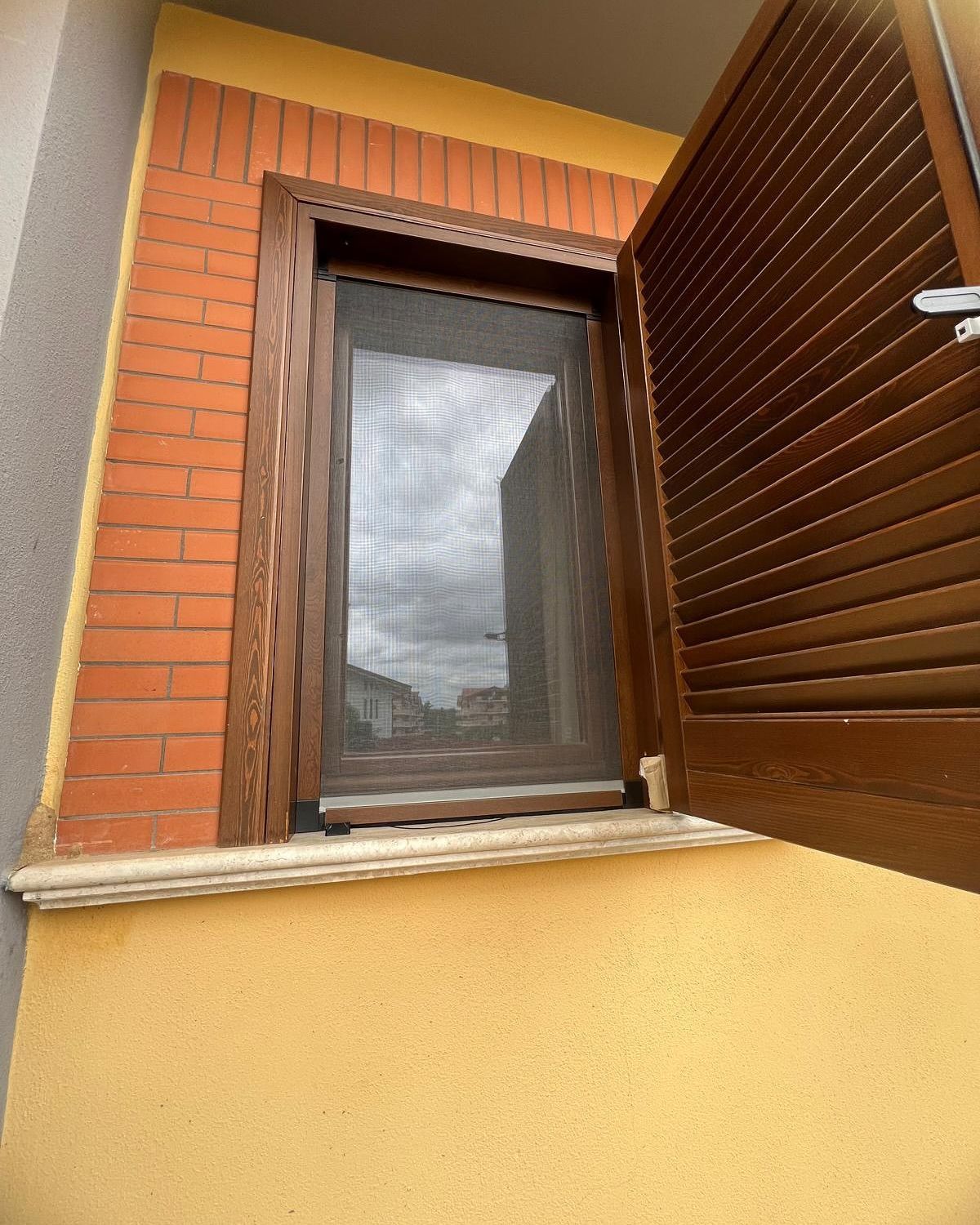 Una finestra con le persiane aperte su un edificio in mattoni