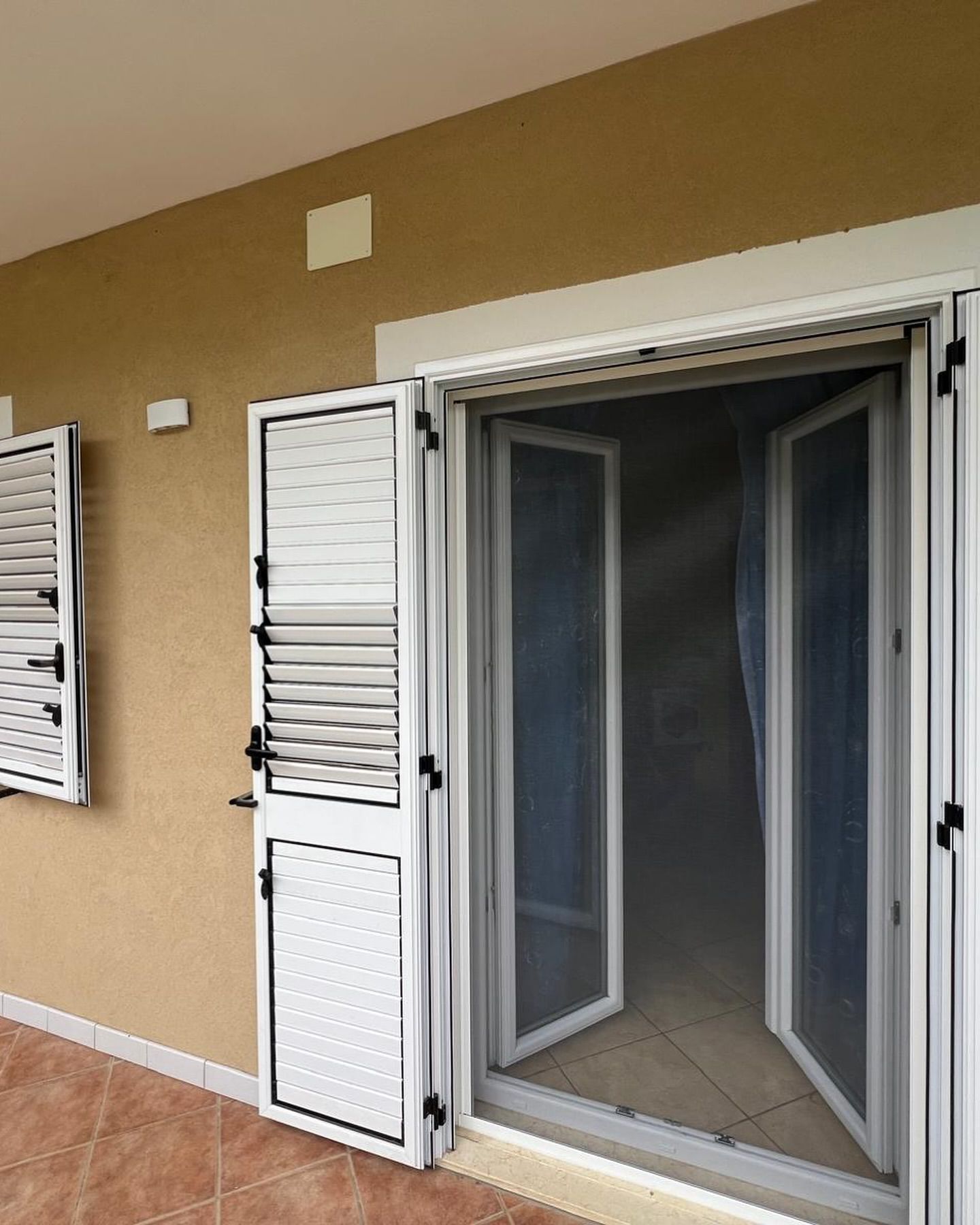 Una porta scorrevole in vetro con persiane ai lati