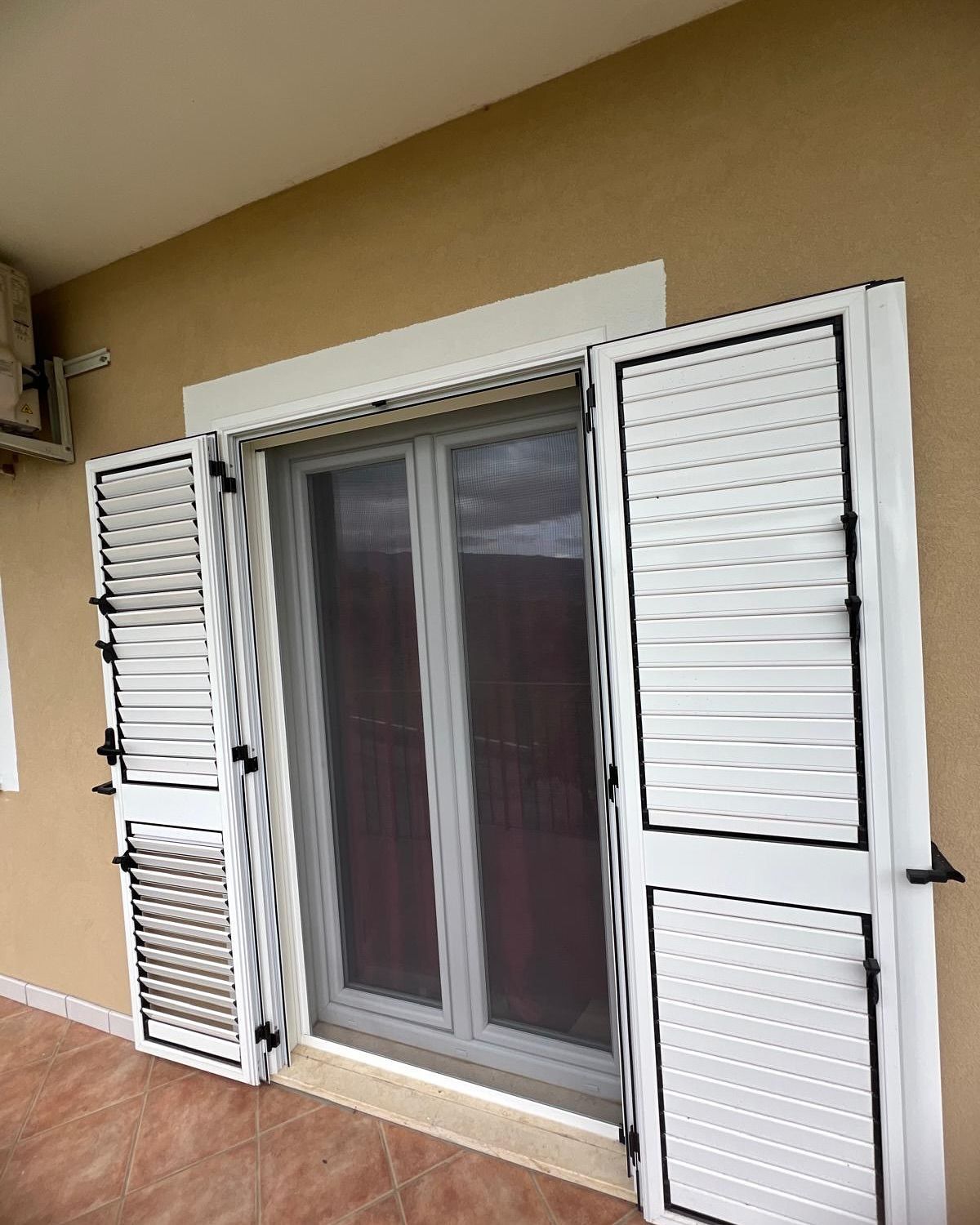 Una porta scorrevole in vetro con persiane bianche.
