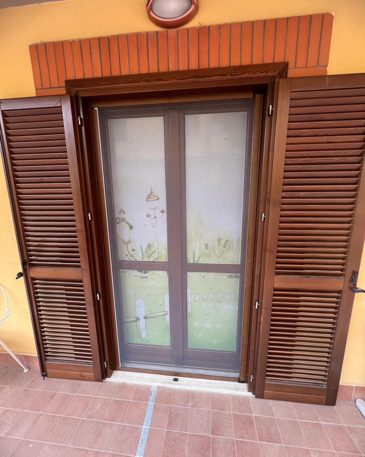 Una porta con persiane e una zanzariera