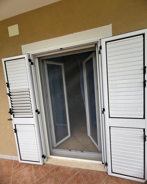 Una porta con le persiane bianche è aperta su una stanza