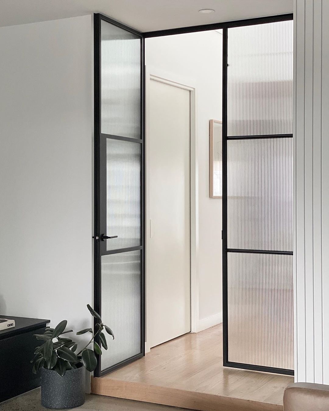 Un soggiorno con una porta scorrevole in vetro che conduce a un corridoio.