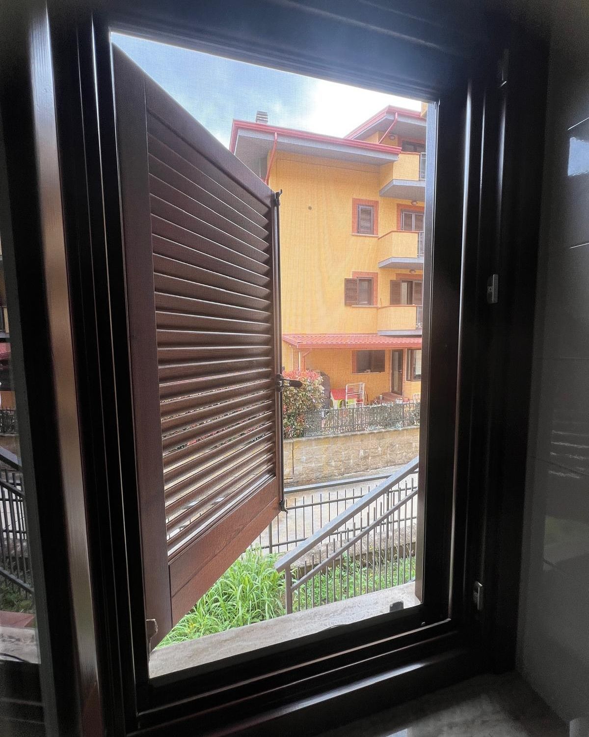 Una finestra con le persiane aperte e un edificio sullo sfondo.