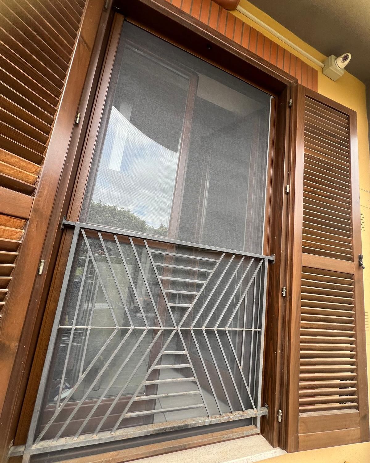 Una finestra con una zanzariera e persiane di legno