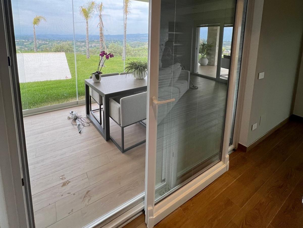 Una porta scorrevole in vetro che conduce a un patio con tavolo e sedie.