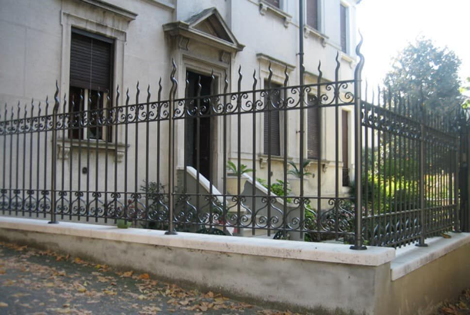 Una recinzione in ferro battuto circonda l'ingresso di un edificio