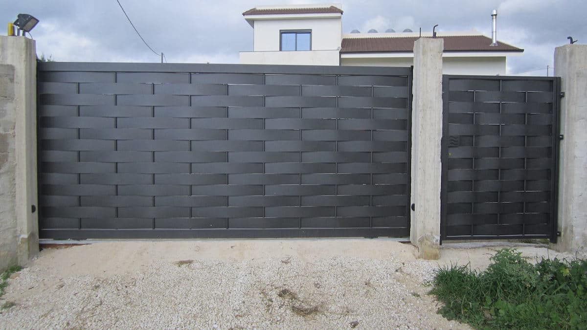 Un cancello scorrevole nero è davanti a una casa