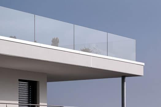 Un balcone con una ringhiera in vetro e un cielo azzurro sullo sfondo