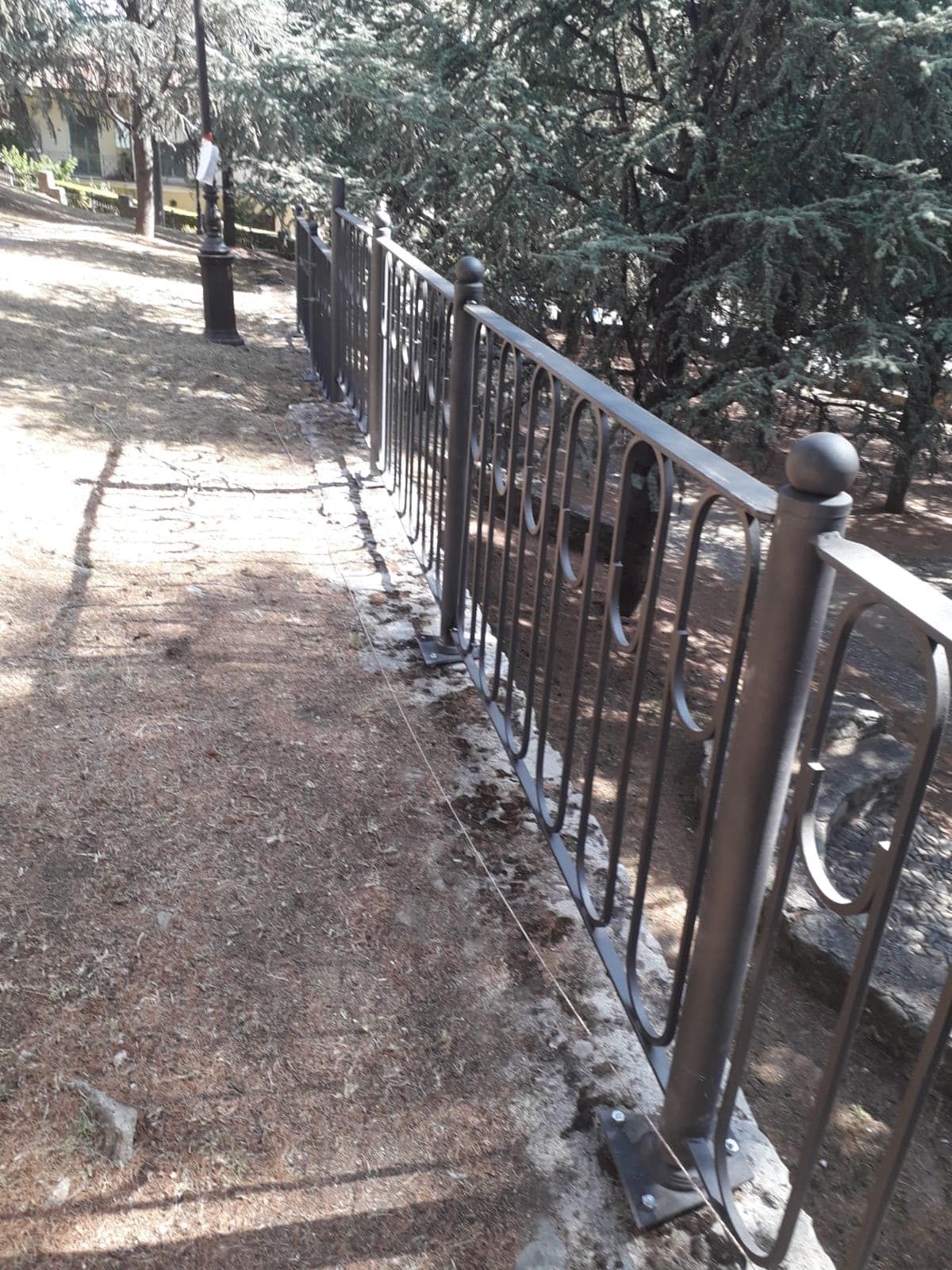 Una recinzione in ferro battuto lungo un sentiero in un parco