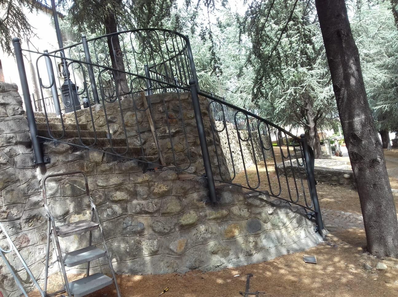 Una ringhiera in ferro battuto è posta in cima a un muro di pietra.