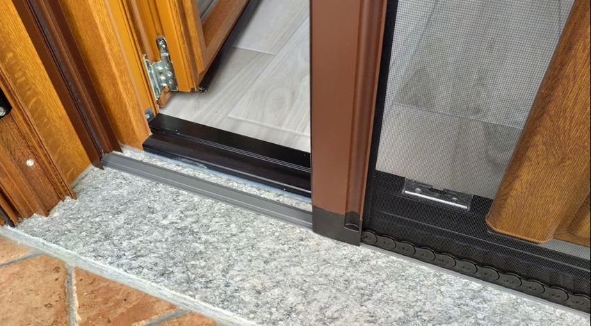 Primo piano di una porta scorrevole in vetro con una zanzariera.