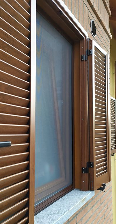 Una finestra con persiane di legno e una zanzariera