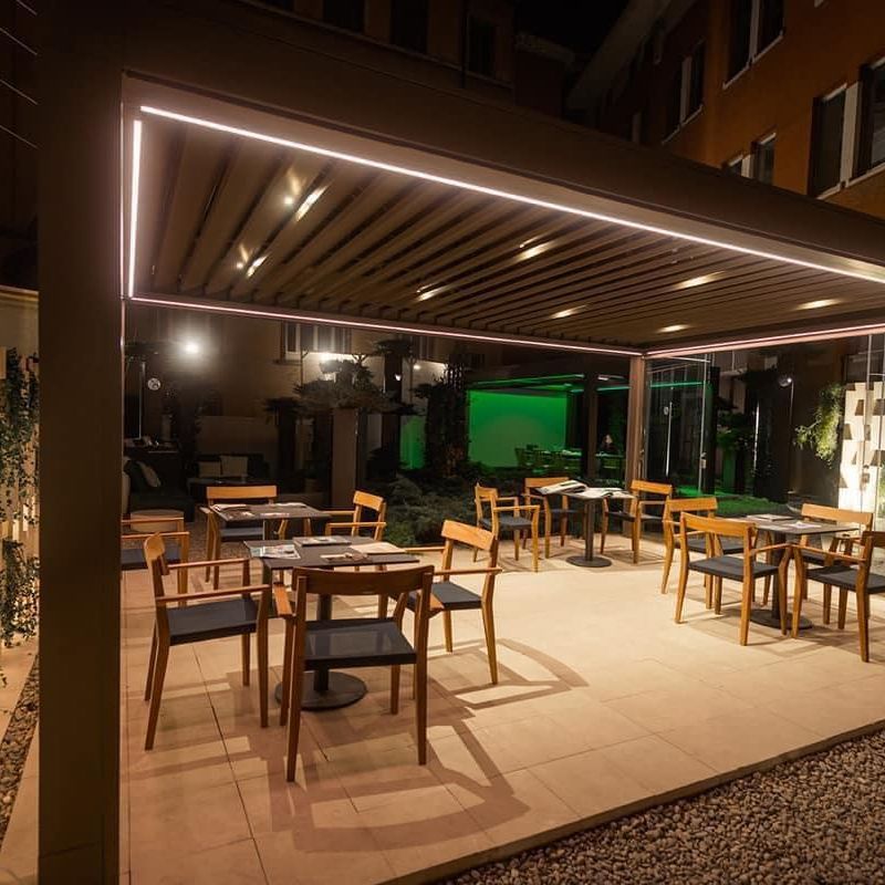 Un ristorante con tavoli e sedie sotto un pergolato di notte