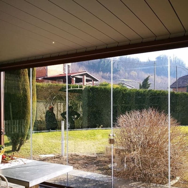 Un patio con tavolo e sedie dietro una parete di vetro