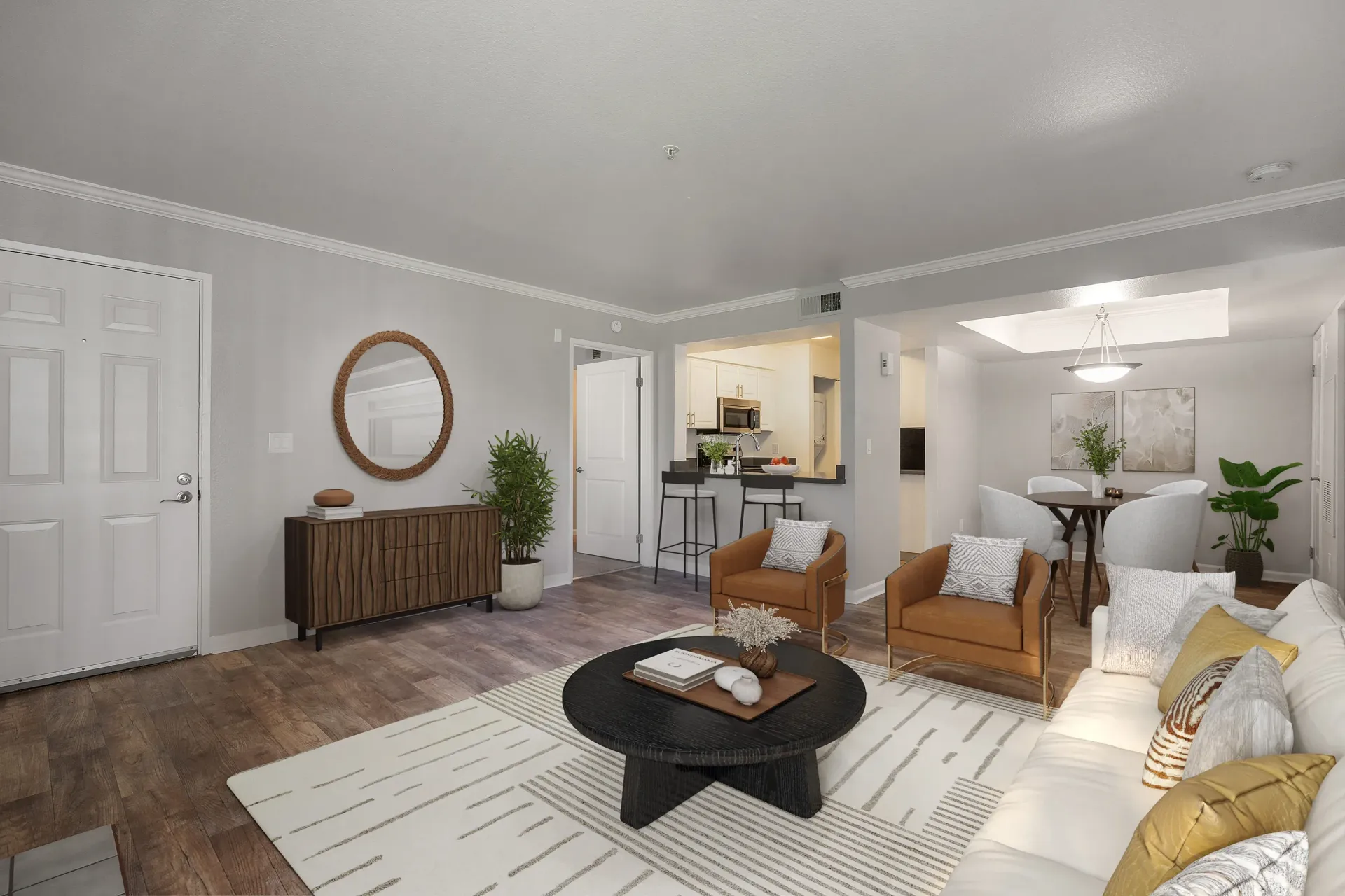 Open-concept living room in an apartment with a sofa, two armchairs, rug, and a kitchen bar.